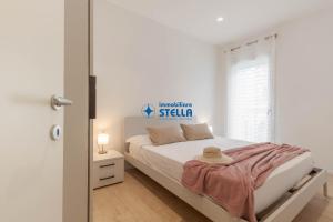 a white bedroom with a bed and a window at Condominio Rossella in Lido di Jesolo