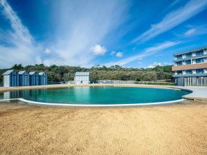 an empty swimming pool with a building in the background at Côte Ouest Hôtel Thalasso & Spa Les Sables d'Olonne - MGallery in Les Sables-d'Olonne