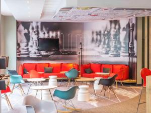 une chambre avec un canapé rouge, des tables et des chaises dans l'établissement ibis Nantes Centre Tour Bretagne, à Nantes