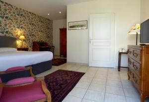 a bedroom with a bed and a door and a chair at Logis Hôtel La Tonnellerie in Beaugency