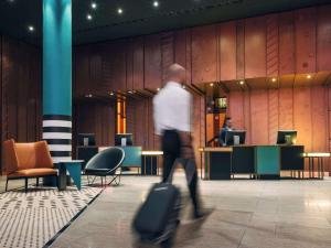 a man walking through a lobby with luggage at Pullman Berlin Schweizerhof in Berlin