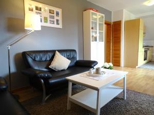uma sala de estar com um sofá de couro preto e uma mesa de centro em Bauernhaus FeWo 3 em Grömitz
