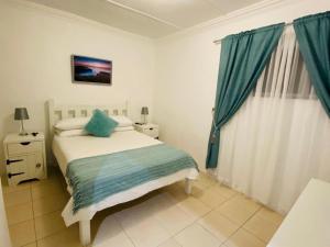 a bedroom with a bed with blue pillows on it at Mariette's Cottage in Arniston