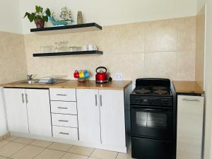 a kitchen with a black stove and a sink at Mariette's Cottage in Arniston