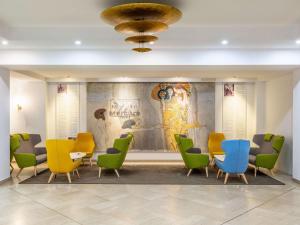 une salle d'attente avec des chaises et des tables colorées et une fresque murale. dans l'établissement Hotel Mercure Wien Westbahnhof, à Vienne