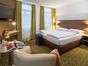 um quarto de hotel com uma cama grande e uma cadeira em Hotel Mercure Wien Westbahnhof em Viena