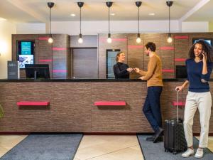two people standing in front of a reception counter at Hotel Mercure Wien Westbahnhof in Vienna