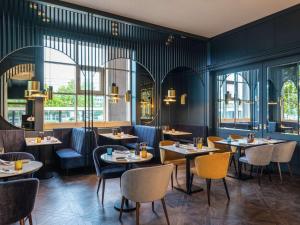 restauracja ze stołami, krzesłami i oknami w obiekcie Pullman Stuttgart Fontana w Stuttgarcie