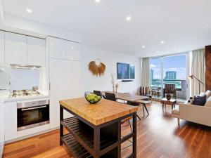 The Sebel Residences Melbourne Docklands Serviced Apartments في ملبورن: مطبخ وغرفة معيشة مع طاولة وأريكة