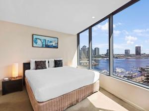 sypialnia z dużym łóżkiem i dużym oknem w obiekcie The Sebel Residences Melbourne Docklands Serviced Apartments w Melbourne