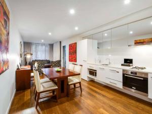 The Sebel Residences Melbourne Docklands Serviced Apartments في ملبورن: مطبخ وغرفة طعام مع طاولة وكراسي خشبية
