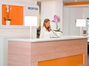 a woman talking on a phone at a reception desk at Ibis budget Wien Messe in Vienna