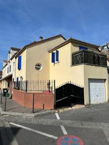 une maison blanche avec des fenêtres bleues et un garage dans l'établissement Maison 8 voyageurs à 15mn des champs élysées, à Asnières-sur-Seine