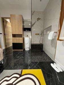 La salle de bains est pourvue d'une douche et d'un sol jaune et noir. dans l'établissement Maison 8 voyageurs à 15mn des champs élysées, à Asnières-sur-Seine