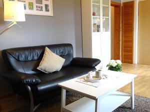 um sofá de couro preto numa sala de estar com uma mesa de centro em Bauernhaus FeWo 3 em Grömitz