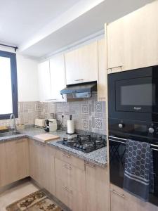 uma cozinha com um fogão e um micro-ondas em La perle de maraval em Orã
