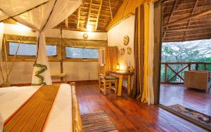 Schlafzimmer mit einem Bett, einem Tisch und einem Fenster in der Unterkunft Embogo Safari Lodges in Katoke