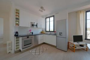 a white kitchen with a refrigerator and a table at Charmant Appartement au Cœur de Boulogne in Boulogne-Billancourt