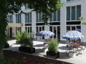 two blue umbrellas and chairs in front of a building at ibis Styles Rastatt Baden-Baden in Rastatt