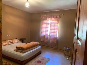 een slaapkamer met een bed en een raam met jaloezieën bij Guest House Tigminou in Setti Fatma