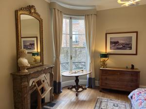 a room with a mirror and a table and a window at Les Suites de L’Opéra in Vichy