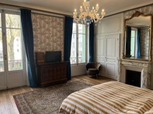 a bedroom with a bed and a mirror and a chandelier at Les Suites de L’Opéra in Vichy