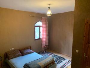 een kleine slaapkamer met een bed en een raam bij Guest House Tigminou in Setti Fatma