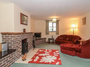 sala de estar con chimenea y sofá rojo en Cartshed Cottage, en Weymouth