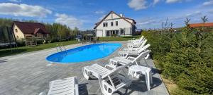 a group of white chairs and a swimming pool at Mazurskie Wzgórze BIS z basenem 1i2 in Rydzewo