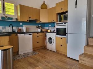 una cocina con electrodomésticos blancos y armarios de madera en Les Trois Chênes, en Les Angles