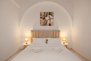 a bedroom with a white bed with two lamps at Nevma Suites in Firostefani