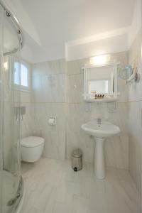 a white bathroom with a sink and a toilet at Nevma Suites in Firostefani