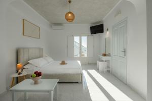 a white bedroom with a bed and a table at Nevma Suites in Firostefani