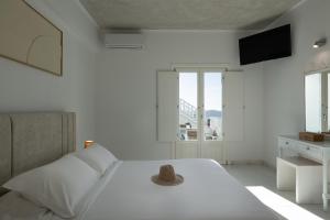 a white bedroom with a bed with a hat on it at Nevma Suites in Firostefani