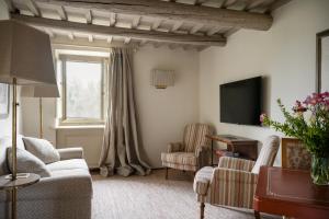 サン・ジュスティーノ・ヴァルダルノにあるIl Borro Relais & Châteauxのリビングルーム(ソファ、椅子2脚、テレビ付)