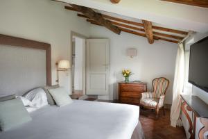 a bedroom with a white bed and a chair at Il Borro Relais & Châteaux in San Giustino Valdarno