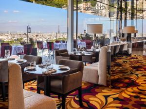 un restaurante con mesas y sillas y vistas a la ciudad en SO/ Paris Hotel en París