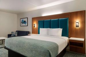Una habitación de hotel con una cama grande y una silla. en Wingate by Wyndham Williamsburg, en Williamsburg