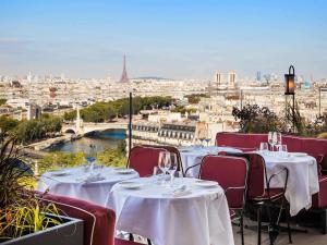 een restaurant met tafels en stoelen en uitzicht op de stad bij SO/ Paris Hotel in Parijs