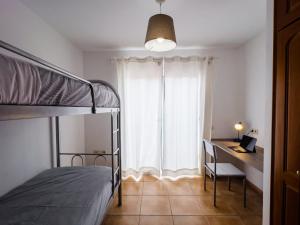 a bedroom with a bed and a desk and a window at Casa Mela in La Oliva