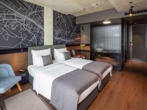 a hotel room with two beds and a tv at Mövenpick Zagreb in Zagreb