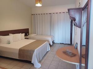 a hotel room with two beds and a table at Pousada Vivenda Oriente in São José da Coroa Grande