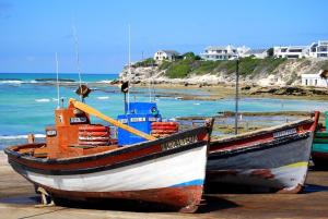 two boats sitting on the beach near the ocean at Mariette's Cottage in Arniston