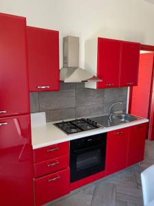 a red kitchen with a stove and a sink at Rossa Chupiteria The Time Avanzato in Licata