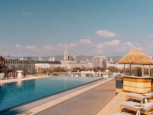 a swimming pool on the roof of a building with a city at The Hoxton Vienna in Vienna