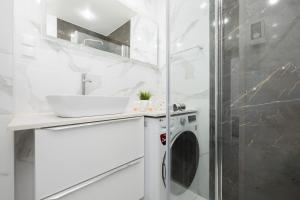 ein Badezimmer mit einem Waschbecken und einer Waschmaschine in der Unterkunft Schillera Apartments Warsaw by Renters in Warschau