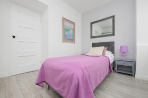 ein weißes Schlafzimmer mit einer rosa Decke auf einem Bett in der Unterkunft Schillera Apartments Warsaw by Renters in Warschau