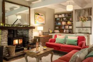 a living room with a red couch and a fireplace at Geranium Cottage in Port Isaac