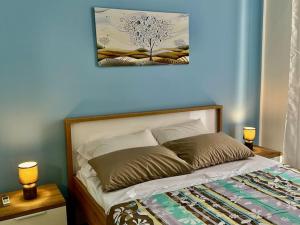 een slaapkamer met een bed met 2 lampen en een blauwe muur bij Casa Felice in Siracusa