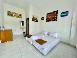 biała sypialnia z łóżkiem i zdjęciami na ścianie w obiekcie MULIA INN Denpasar Imam Bonjol w mieście Seminyak
